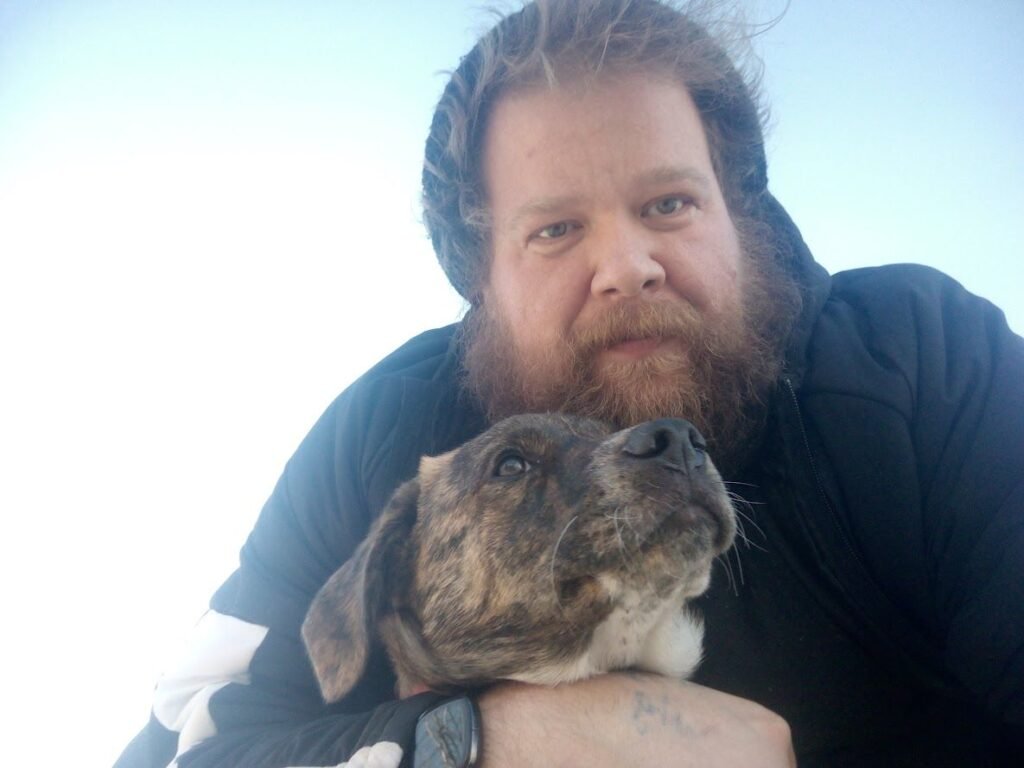 Kevin Duska looks straight at the camera while his loyal service dog Wilco looks up at him